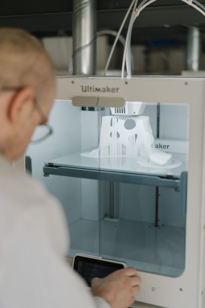 A tech watches a 3D printer quickly producing a piece